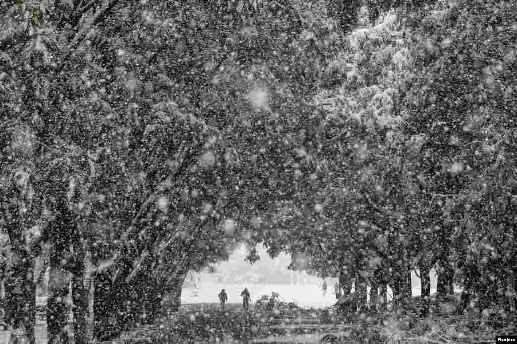 People make their way at the Zappeion area during heavy snowfall in Athens, Greece.