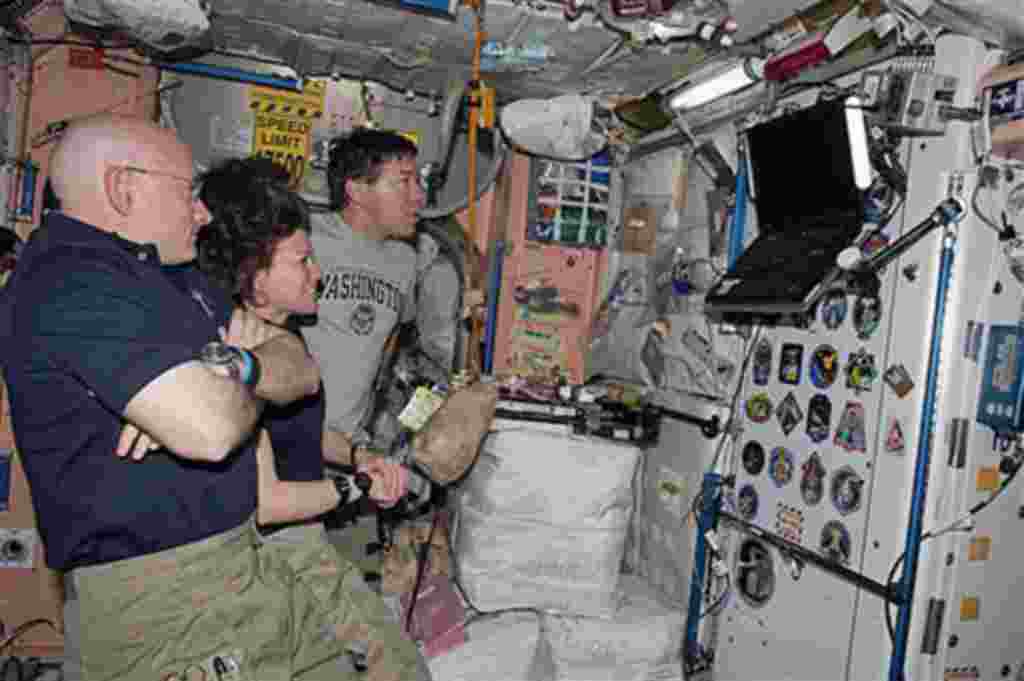 Los astronautas Scott Kelly, Cady Coleman y Michael Barratt observan el monitor del transbordador Discovery mientras este se aleja de la Estación Espacial Internacional.