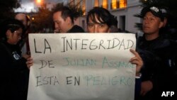 Una mujer sostiene un cartel que dice "La seguridad de Assange está en peligro" mientras se manifiesta en contra del arresto del fundador de WikiLeaks, Julian Assange, frente al Ministerio de Relaciones Exteriores en Quito.
