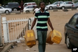 FILE - A man carries empty containers to buy fuel at a petrol station in Abuja, Nigeria. Nigerians are watching eagerly to see if whether Buhari will make good on his plan to take over the oil ministry.