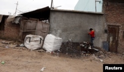 A boy plays with cans over a pile of garbage outside his home in the Villa Palito slum in La Matanza, in the greater Buenos Aires area, July 29, 2015.