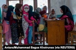 Anak-anak memakai masker pelindung berbaris saat kegiatan belajar mengajar di tengah wabah COVID-19 di Lebak, Provinsi Banten, 4 Agustus 2020. (Foto: Antara/Muhammad Bagus Khoirunas/via Reuters)