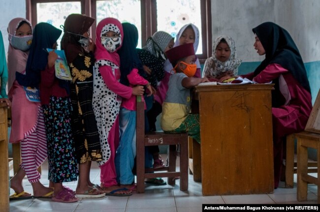 Anak-anak memakai masker pelindung berbaris saat kegiatan belajar mengajar di tengah wabah COVID-19 di Lebak, Provinsi Banten, 4 Agustus 2020. (Foto: Antara/Muhammad Bagus Khoirunas/via Reuters)