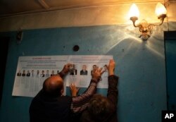 Election officials place pre-election leaflets at a polling station ahead of parliamentary elections in the village of Gusino, outside Smolensk, western Russia, Sept. 17, 2016.