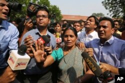 FILE - Journalists crowd around Asha Devi, mother of the victim of the fatal 2012 gang rape on a moving bus, after the Supreme Court verdict in the case, in New Delhi, India, May 5, 2017.