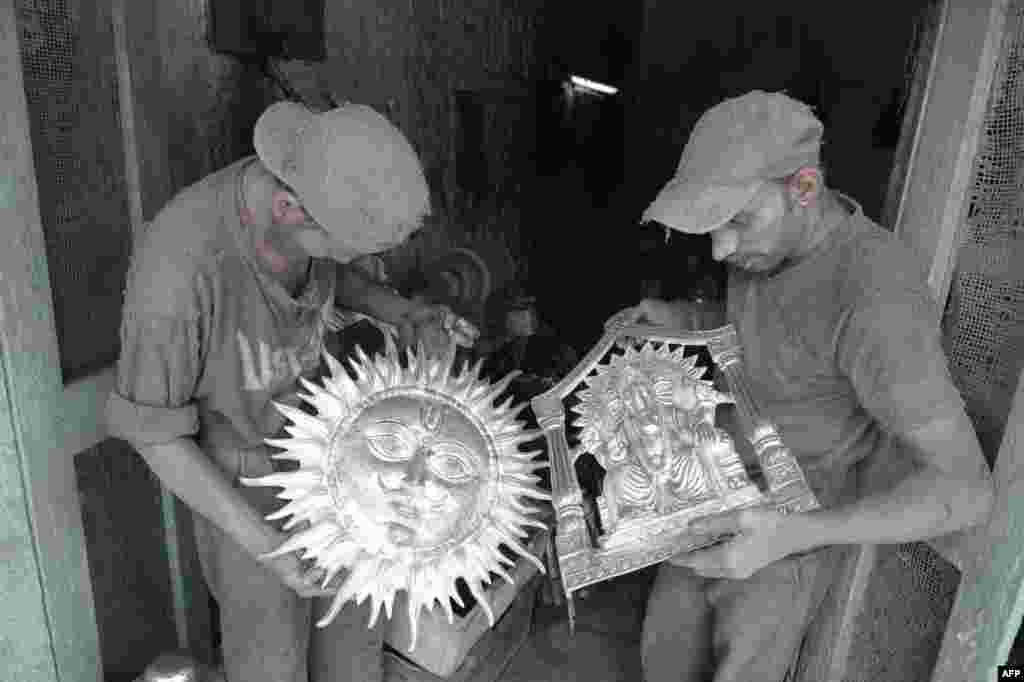 Indian artisans carry metal statues of Hindu deities at a workshop in the old city of Hyderabad.