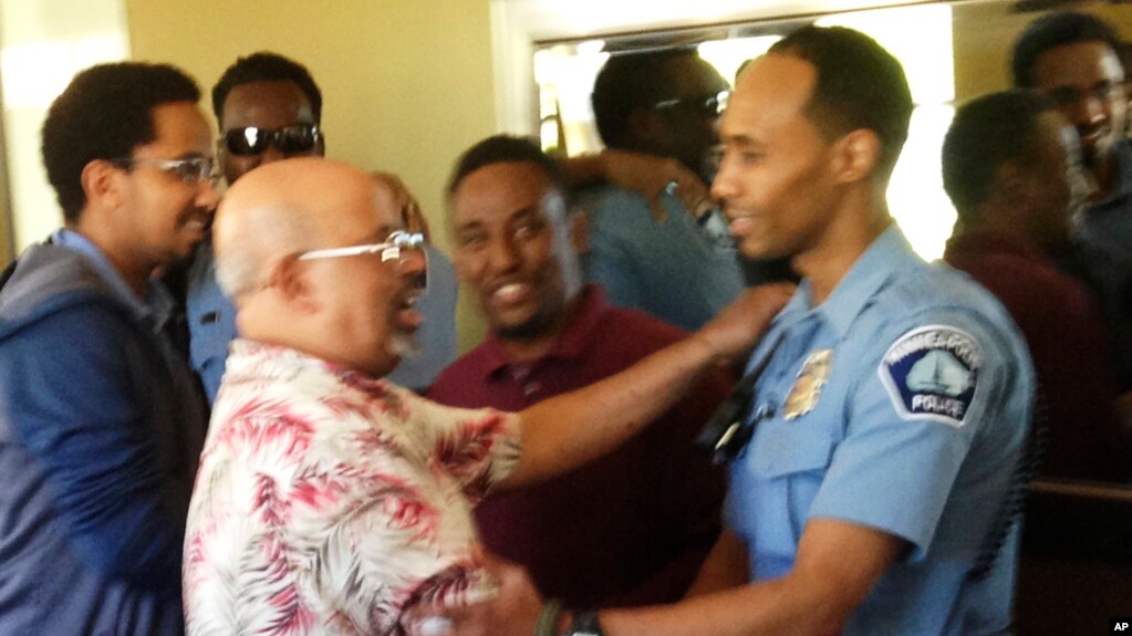 In this May 2016 photo provided by the city of Minneapolis, Officer Mohamed Noor, right, is greeted by a well-wisher at a community event welcoming him to the Minneapolis police force. Noor, a Somali-American, has been identified as the officer who fatally shot Justine Damond, of Sydney, Australia, on July 15, 2017.