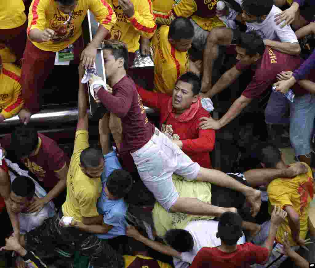 A Catholic devotee manages to get closer to kiss the cross of the centuries-old image of the Black Nazarene in a raucous celebration on its feast day in Manila, Philippines. 