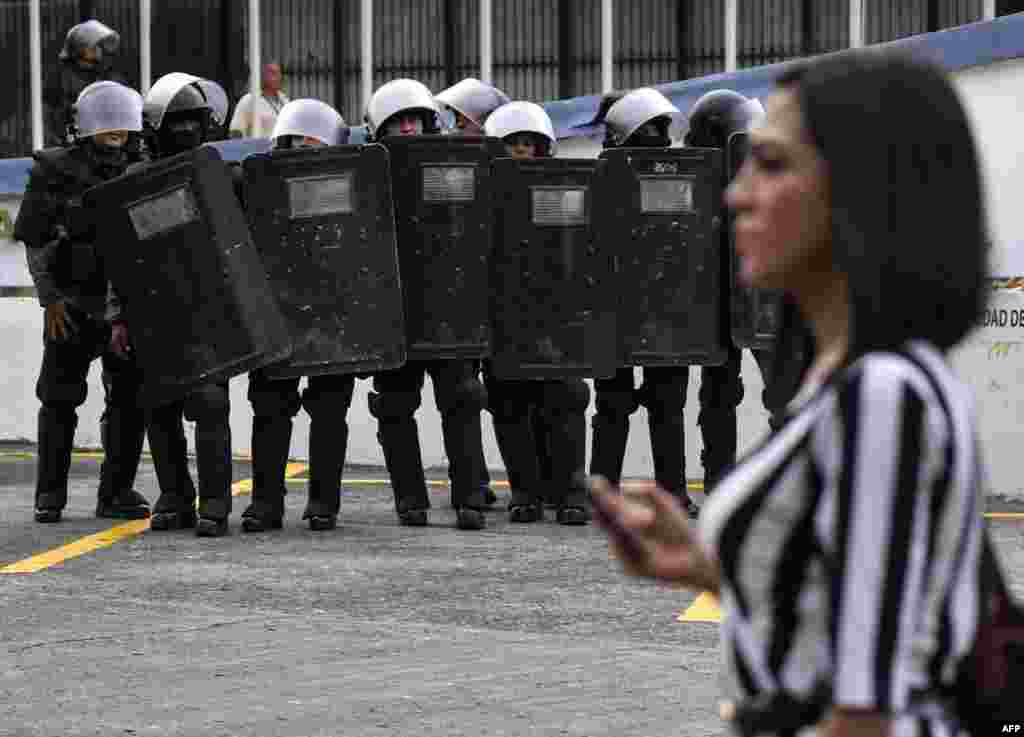 Una mujer camina junto a un grupo de policías antidisturbios durante la protesta. 