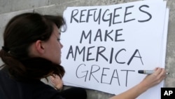 Protester Emily Nostro prepares a sign for a rally against President Donald Trump's executive order on Muslim immigration, Jan. 22, 2017, in Miami. Protesters manifested their opposition to Trump's executive order restricting immigration from some Middle Eastern and African countries.