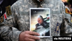 A demonstrator holds the picture of assasinated Iranian Major-General Qassem Soleimani during a protest in Tehran, Jan. 3, 2020.