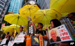 Para pengunjuk rasa anti-Beijing, yang memegang payung kuning dan gambar aktivis hak asasi manusia Wang Qingying, memprotes untuk menuntut pembebasan Wang, di Hong Kong. (Foto: AP)