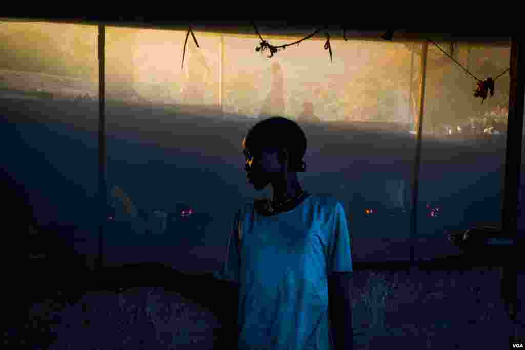 A girl stand outside the smoke house, where many internally displaced people cook, while staying in the hospital compound. (Adam Bailes/VOA News)