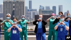 FILE - Healthcare professionals pose a group photo on a helipad at Memorial Hermann Hospital after the U.S. Navy's Blue Angels flyover of the Medical Center Wednesday, May 6, 2020, in Houston.