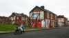 FILE - A woman pushes a stroller along a semi-derelict street in the Gresham area of Middlesbrough, northern Britain, Jan. 20, 2016. Asylum seekers in the northern English town of Middlesbrough are often suffering abuse.