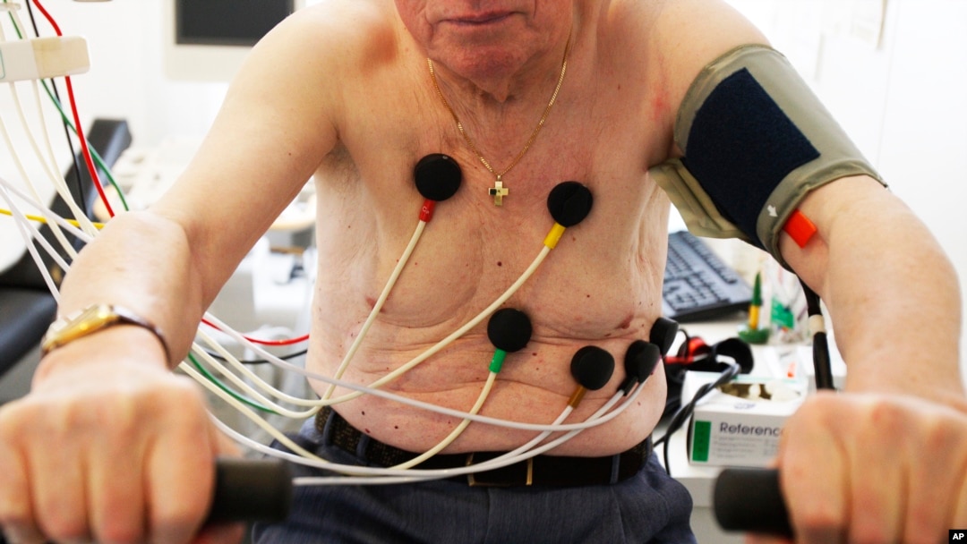 FILE - A man sits on an ergometer during an electrocardiogram in a doctor's surgical office.