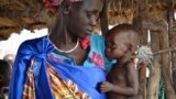 FILE - Elizabeth Nyakoda holds her severely malnourished 10-month-old daughter at the feeding center for children in Jiech, Ayod County, South Sudan, Dec. 10, 2017. 