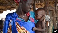 FILE - Elizabeth Nyakoda holds her severely malnourished 10-month-old daughter at the feeding center for children in Jiech, Ayod County, South Sudan, Dec. 10, 2017. 