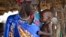 FILE - Elizabeth Nyakoda holds her severely malnourished 10-month-old daughter at the feeding center for children in Jiech, Ayod County, South Sudan, Dec. 10, 2017. 