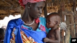 FILE - Elizabeth Nyakoda holds her severely malnourished 10-month old daughter at the feeding center for children in Jiech, Ayod County, South Sudan, Dec. 10, 2017. 