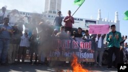 Para pemrotes Muslim berdoa saat mereka membakar sebuah patung dalam aksi unjuk rasa anti-LGBT di Banda Aceh, Indonesia, Jumat, 2 Februari 2018. Ratusan orang berdemonstrasi menentang penyelidikan polisi setempat yang menangkapi perempuan transgender dan mempermalukan mereka di hadapan publik. 