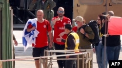 Newly-released Israeli-Argentinian hostage Yair Horn (C), flanked by relatives and security forces, waves after disembarking from a military helicopter on the heliport of the Tel Aviv Sourasky Medical Center (Ichilov), Feb/ 15, 2025. 