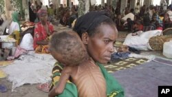 Une mère venant du sud de la Somalie porte son enfant mal nourri (Mogadiscio, 28 août 2011)