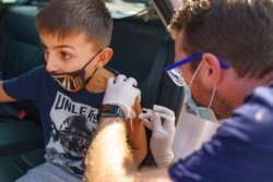 A 10-year-old boy reacts to an influenza vaccine during an annual flu vaccination event at the Exposition Park in Los Angeles, Oct. 17, 2020.