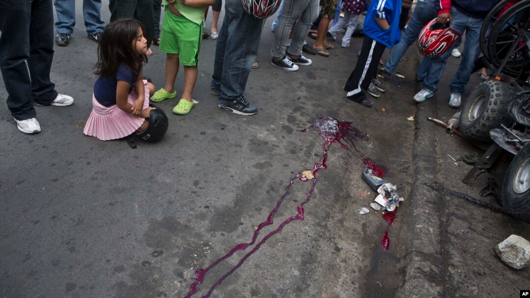 Seorang anak perempuan menutup matanya saat duduk di lokasi pembunuhan di Tegucigalpa, Honduras (1/12). (AP/Esteban Felix)
