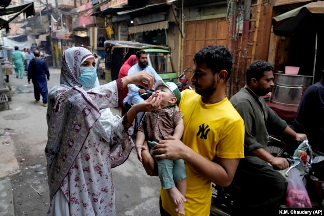 A health worker gives a polio vaccine to a child in a downtown area of Lahore, Pakistan, Monday, Sept. 9, 2024. (AP Photo/K.M. Chaudary)