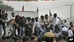 India's opposition Bharatiya Janata Party activists shouting anti-government slogans lose their balance while standing atop police barricades during a protest against the reported corruption in the recently held Commonwealth Games in New Delhi, India, Nov