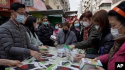 People buy face masks from a street vendor in Hong Kong, Saturday, Feb, 1, 2020.