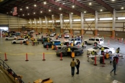 FILE - Cars pull in to nursing stations for the COVID-19 vaccine rollout at the Davis County Legacy Center in Farmington, Utah, Jan. 12, 2021.