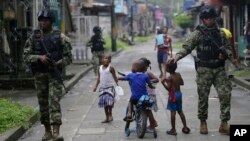 Niños juegan mientras fuerzas especiales de la Armada patrullan en Buenaventura, la principal ciudad puerto en la costa del Pacífico en Colombia.