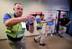 Police officers David Riggall, left, and Nick Guadarrama, center, show students Stephen Hatherley, center rear, and Chris Scott, right rear, how to clear a hallway intersection during a security training session at Fellowship of the Parks campus