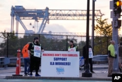 Dockworkers strike in front of an entrance to a container terminal near Boston Harbor, Oct. 1, 2024, in Boston.