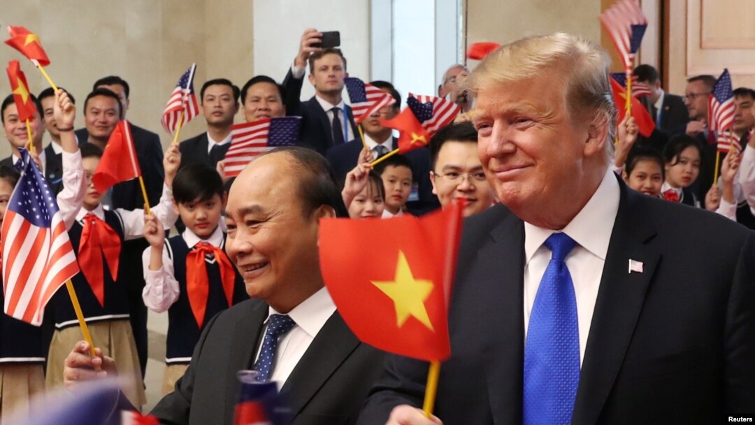 Tổng thống Donald Trump (phải) vẫy lá cờ Việt Nam trong khi Thủ tướng Phúc vẫy lá cờ Mỹ tại một buổi đón tiếp nguyên thủ Mỹ ở Văn phòng Chính phủ ở Hà Nội hôm 27/2.