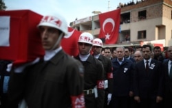 FILE - Turkey's Defense Minister Hulusi Akar, third right, attends a funeral ceremony for Halil Ibrahim Akkaya, one of Turkish soldiers killed in Syria, in Bahce, Turkey, Feb. 28, 2020.