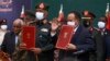 In this photo provided by the Sudan Transitional Sovereign Council, Sudan's top general Abdel Fattah Al-Burhan, center left, and Prime Minister Abdalla Hamdok hold documents during a ceremony to reinstate Hamdok.