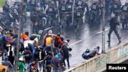 Un miembro de las fuerzas antimotines apunta con una pistola hacia los manifestantes durante una protesta antigubernamental en Caracas, el lunes 19 de junio.