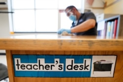 Des Moines Public Schools custodian Joel Cruz cleans a teacher's desk in a classroom at Brubaker Elementary School, July 8, 2020, in Des Moines, Iowa.