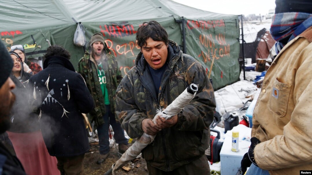 FILE - Oscar High Elk, 26, of the Cheyenne River Sioux Tribe, prays as he and other members of the tribe prepare to evacuate from the main opposition camp against the Dakota Access oil pipeline near Cannon Ball, N.D., Feb. 22, 2017. 