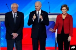 Democratic presidential candidates from left, Sen. Bernie Sanders, I-Vt., former Vice President Joe Biden and Sen. Elizabeth Warren, D-Mass., stand on stage, Feb. 7, 2020, before the start of a Democratic presidential primary debate.