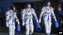 Los astronautas estadounidenses Christina Hammock Koch (i), Nick Hague (d), y el ruso Alexey Ovchinin momentos antes del lanzamiento de la nave Soyuz MS-12 que los llevó a la Estación Espacial Internacional. (AP Foto/Dmitri Lovetsky).