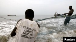 Des pêcheurs tirent leur filet hors de l'eau près de New Kru, Liberia, le 22 novembre 2005.