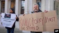 FILE — Protesters stand outside the Supreme Court in London where they were speaking out against a government plan to send migrants to Rwanda, Nov. 15, 2023. 