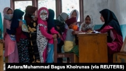 Anak-anak memakai masker pelindung berbaris saat kegiatan belajar mengajar di tengah wabah COVID-19 di Lebak, Provinsi Banten, 4 Agustus 2020. (Foto: Antara/Muhammad Bagus Khoirunas/via Reuters)