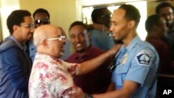 In this May 2016 photo provided by the city of Minneapolis, Officer Mohamed Noor, right, is greeted by a well-wisher at a community event welcoming him to the Minneapolis police force. Noor, a Somali-American, has been identified as the officer who fatally shot Justine Damond, of Sydney, Australia, on July 15, 2017.