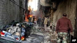 A Syrian soldier, right, and citizens gather at an alley that was destroyed by two cars bombs, at Jaramana neighborhood, in the suburb of Damascus, Syria, Wednesday, Nov. 28, 2012. (AP Photo/SANA)