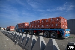 Trucks loaded with aid wait to cross into Gaza from the Egyptian side of the Rafah border crossing, Jan. 19, 2025.